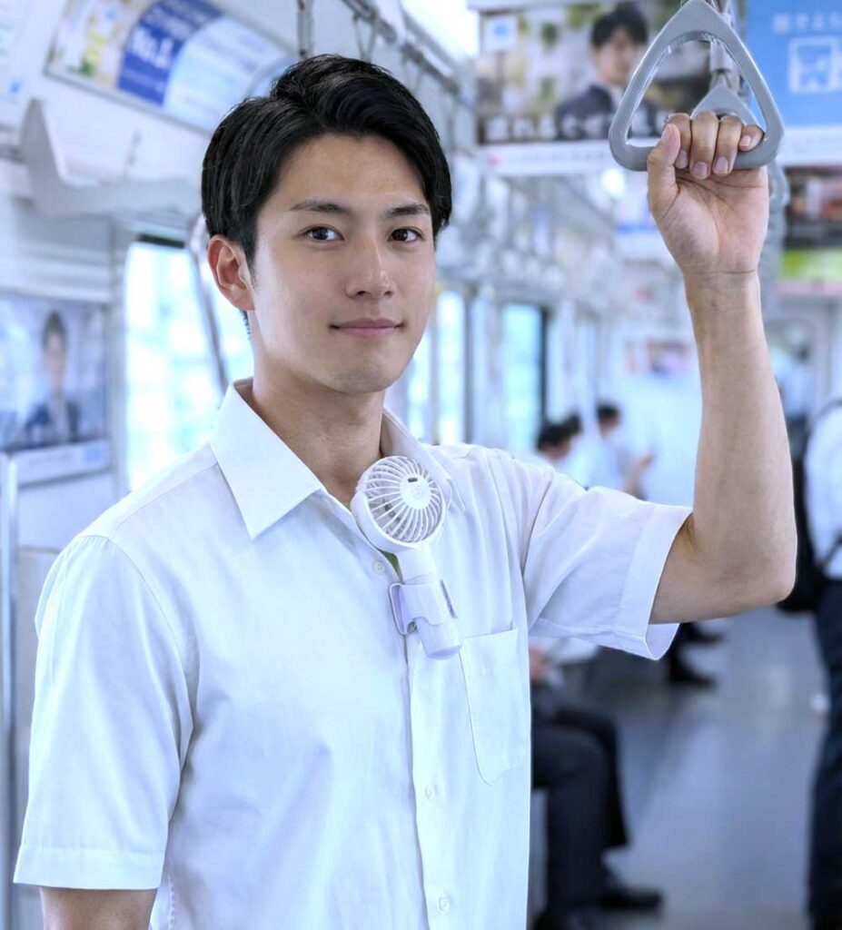 エアシャツ扇風機でシャツ内に送風している男性が電車に乗っている様子