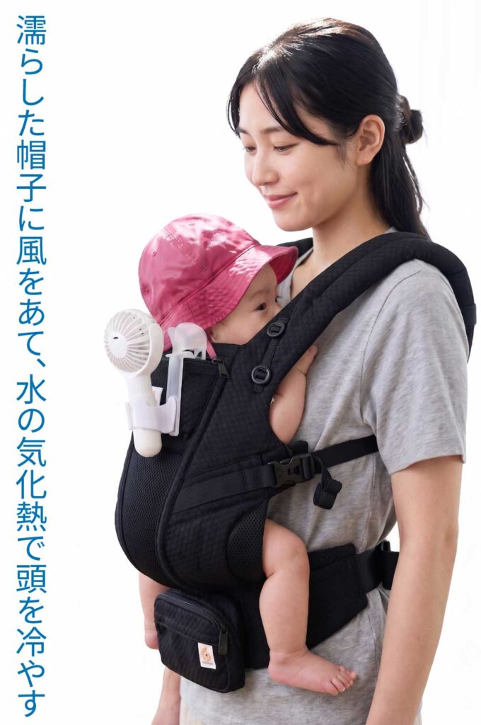 抱っこ紐にハンディファンをつけて水で濡らした帽子へ送風する様子